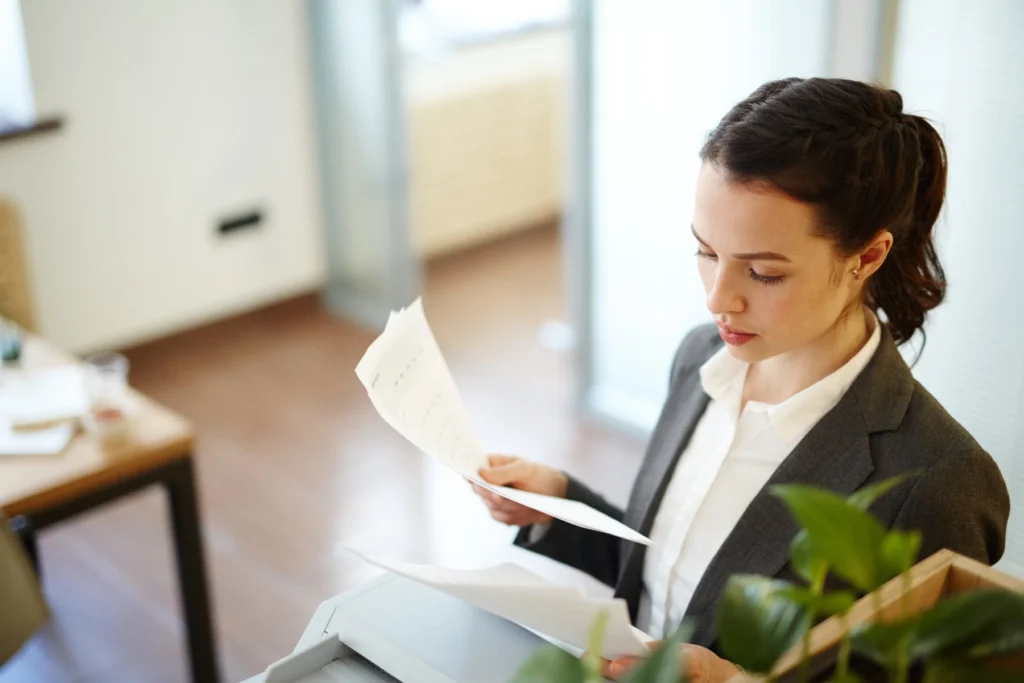 Advogada lê com atenção os documentos de um contrato no escritório
