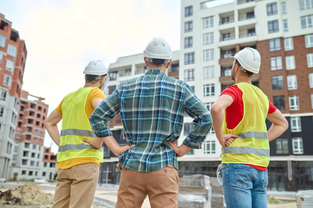 Operários observam prédios residenciais em construção no canteiro de obras